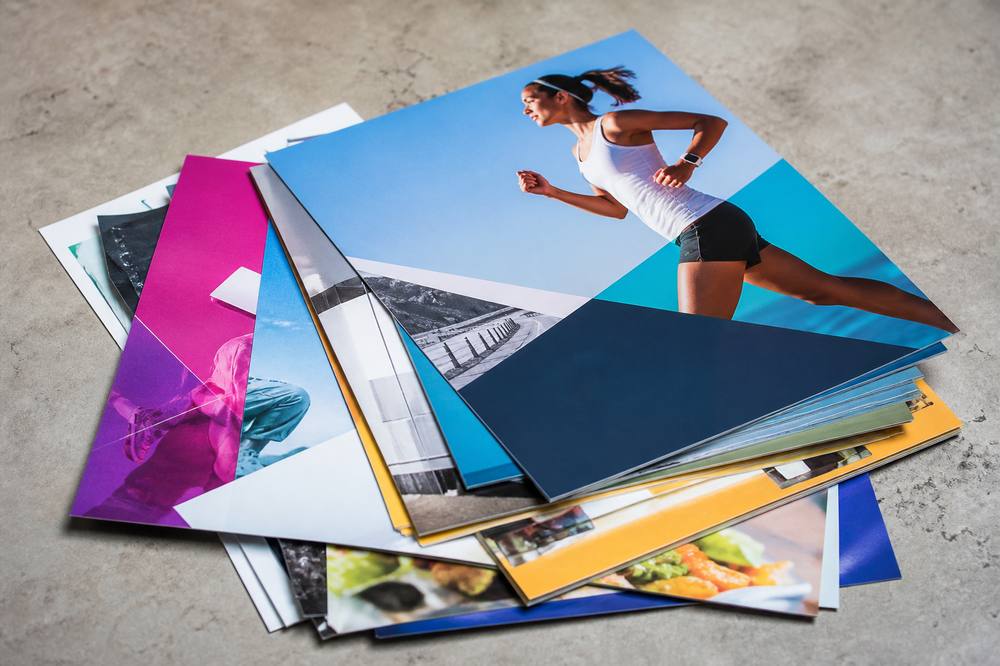 Stack of full-color printed flyers on a concrete surface